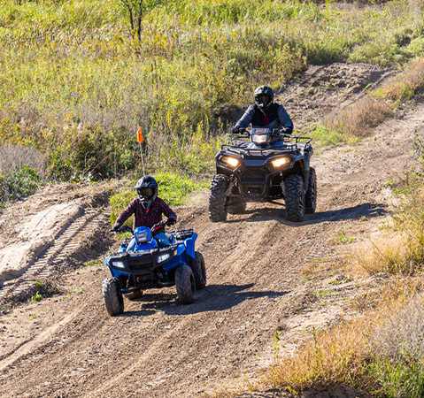 A rider on a 2027 Polaris Sportsman 110 EFI youth ATV showcasing the front and rear racks on a trail.