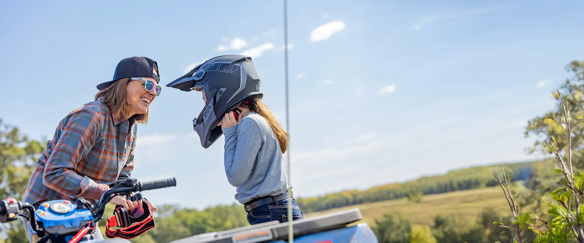 A mom talking to her kid on a 2027 Polaris Sportsman 110 EFI youth ATV.