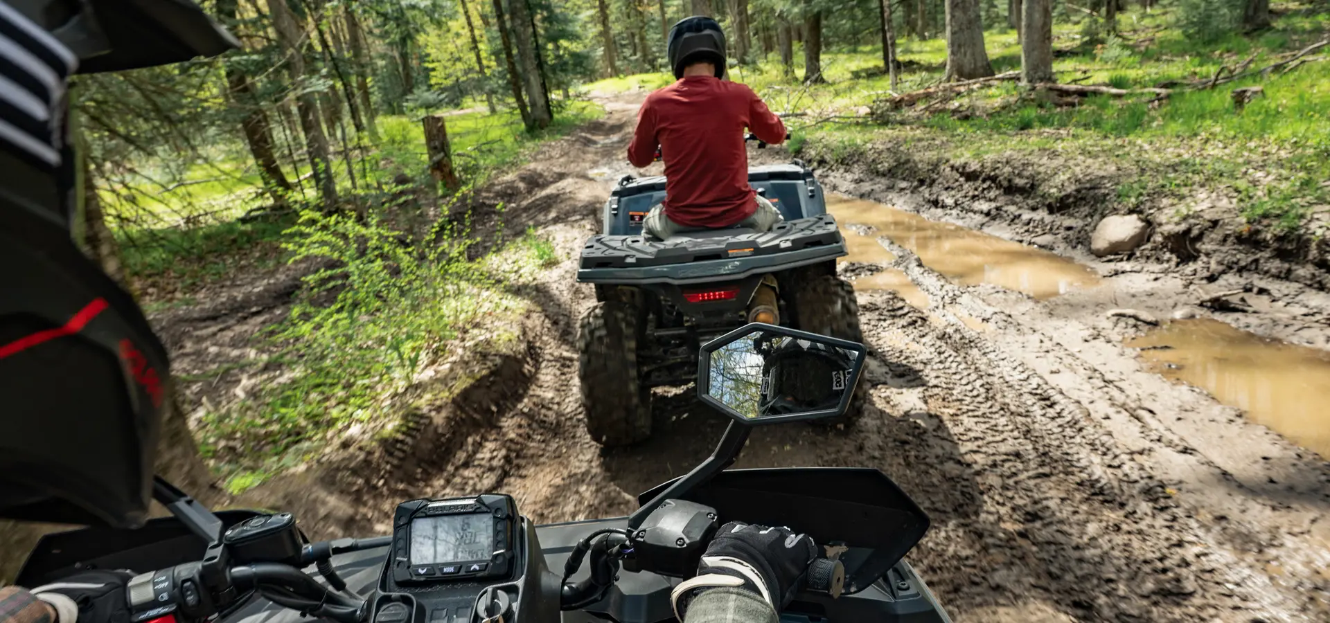A person looking in their handlebar mirror while driving a 2027 Polaris Sportsman 500 ATV.