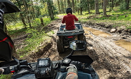 A person looking in their handlebar mirror while driving a 2027 Polaris Sportsman 500 ATV.