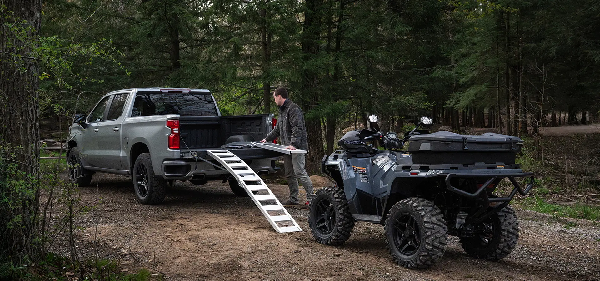 A man grabbing ramps from his truck bed to load up his 2027 Polaris Sportsman 500 ATV.