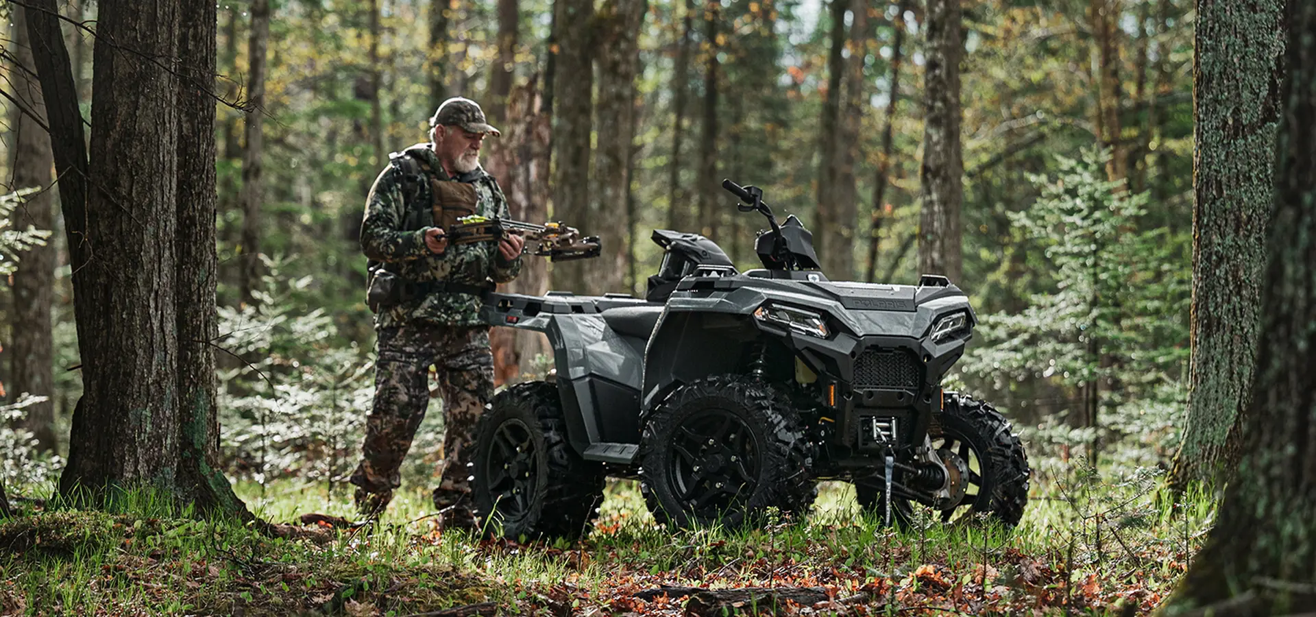 A man grabbing hunting gear from his 2027 Polaris Sportsman 500 ATV.