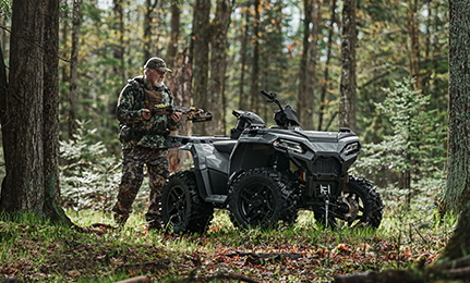 A man grabbing hunting gear from his 2027 Polaris Sportsman 500 ATV.
