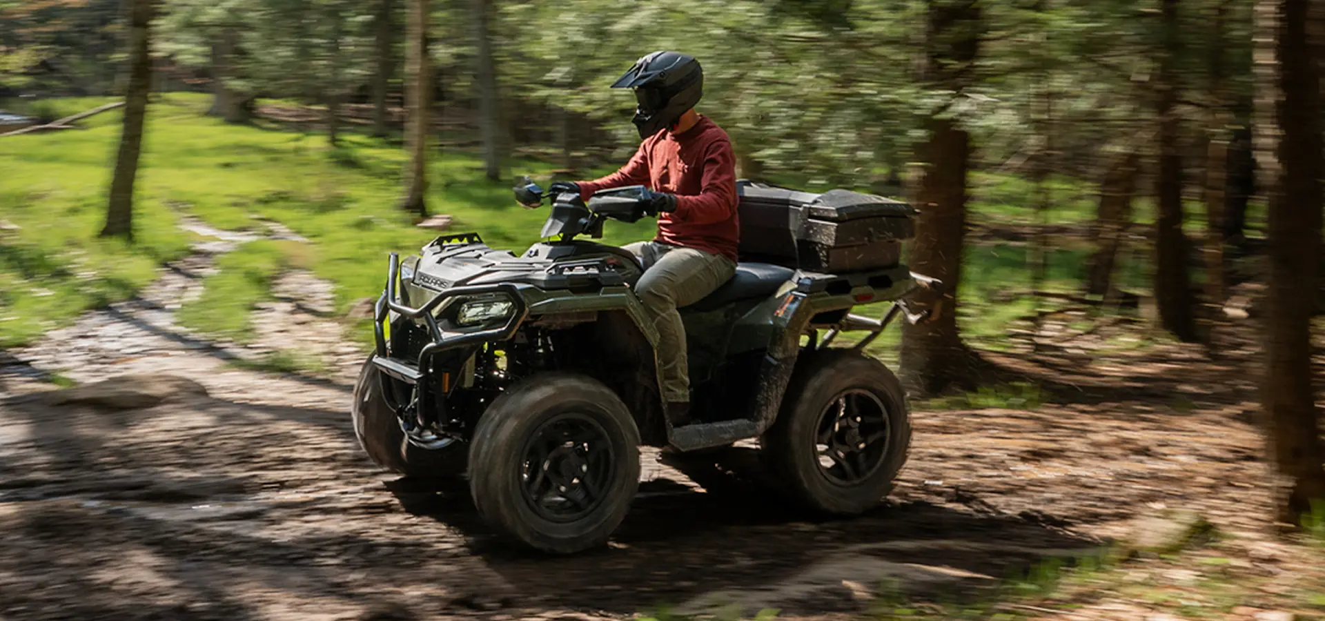A person riding a 2027 Polaris Sportsman 500 ATV down a trail.