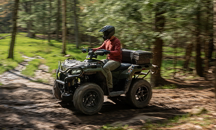 A person riding a 2027 Polaris Sportsman 500 ATV down a trail.