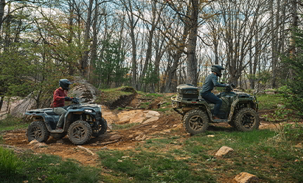 2 people riding 2027 Polaris Sportsman 500 ATVs on a trail in the forest.