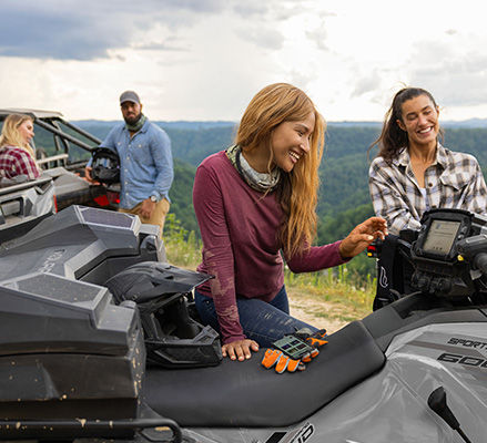 Woman using the RIDE COMMAND touch screen on a 2027 Polaris Sportsman 600 ATV.