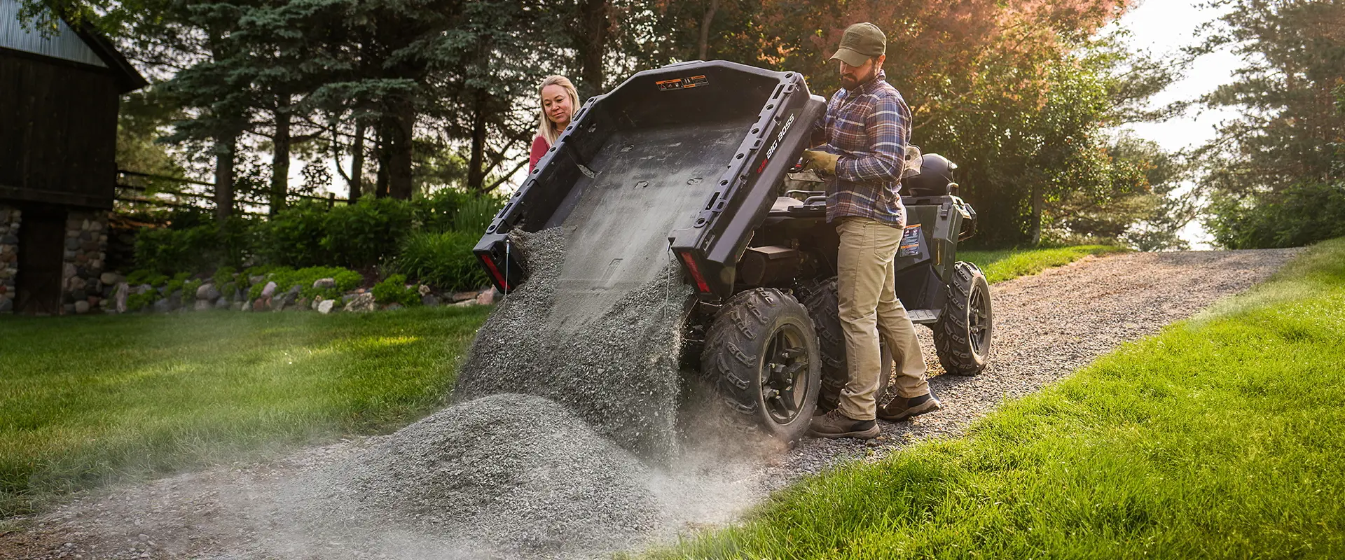 A couple dumping rocks from the cargo box of their 2027 Polaris Sportsman 6x6 600 2-up ATV.