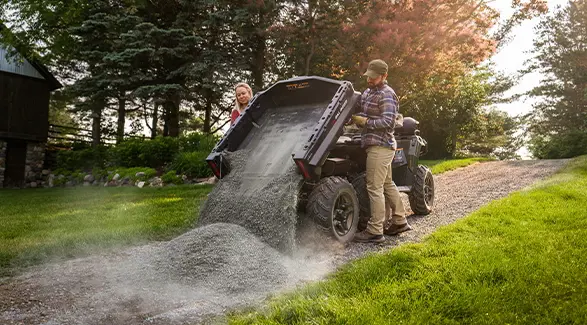 A couple dumping rocks from the cargo box of their 2027 Polaris Sportsman 6x6 600 2-up ATV.
