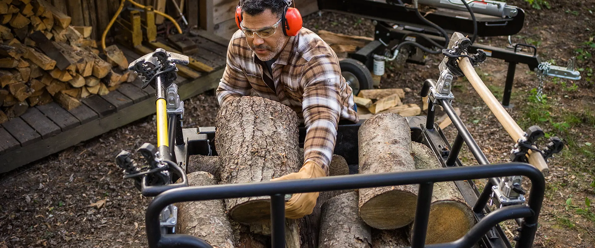 A man unloading firewood from the cargo box of his 2027 Polaris Sportsman 6x6 600 2-up ATV.
