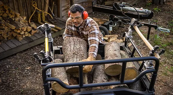 A man unloading firewood from the cargo box of his 2027 Polaris Sportsman 6x6 600 2-up ATV.