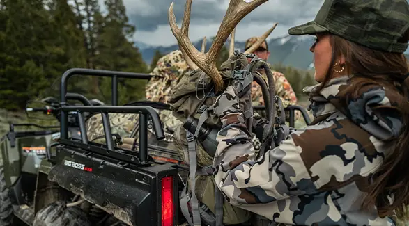A female hunter gearing up with cargo from the box of her 2027 Polaris Sportsman 6x6 600 2-up ATV.
