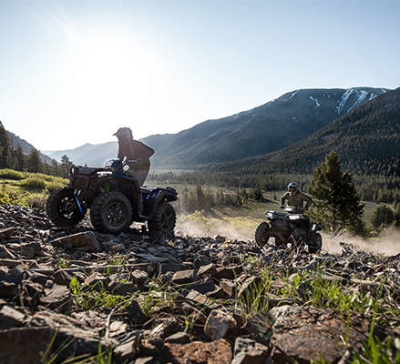 2 riders on 2027 Polaris Sportsman 850 four wheelers riding over rocky terrain.