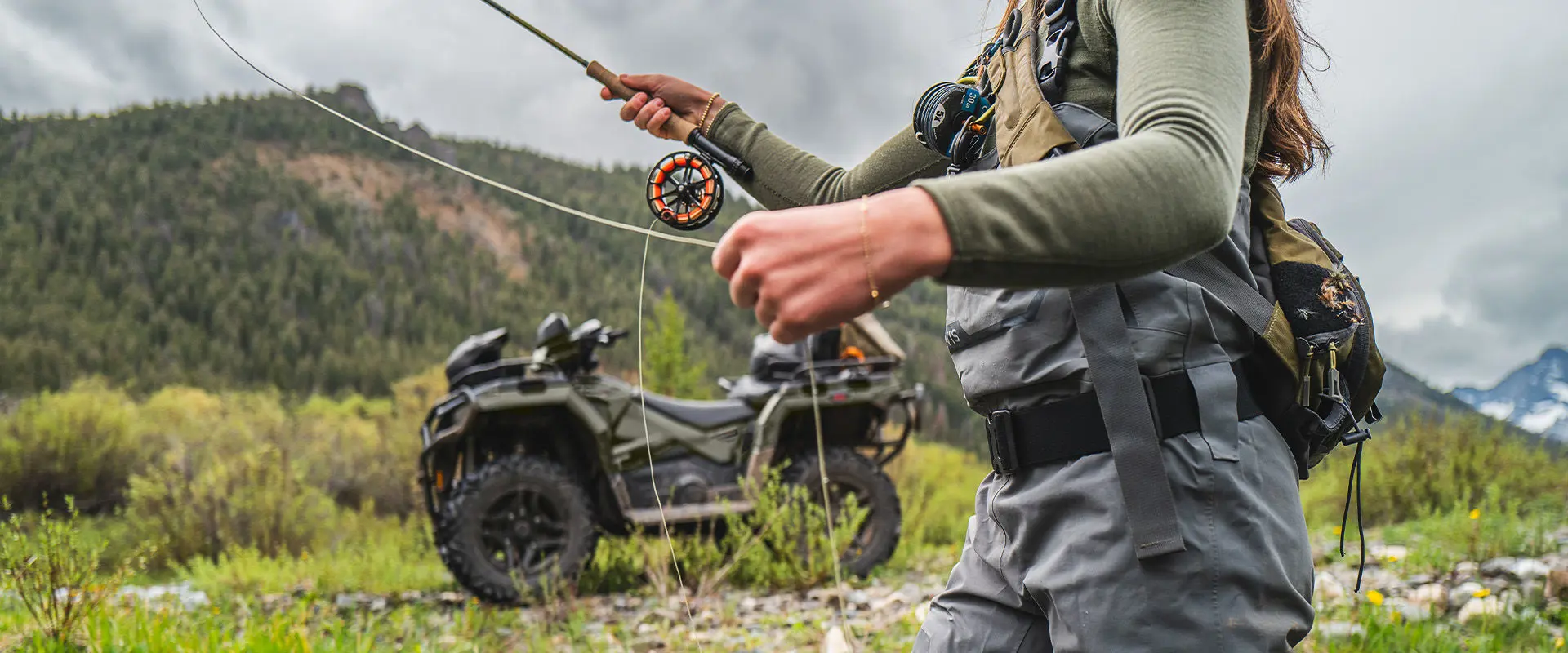 A woman fishing near her 2027 Polaris Sportsman Touring 600 2-up ATV.
