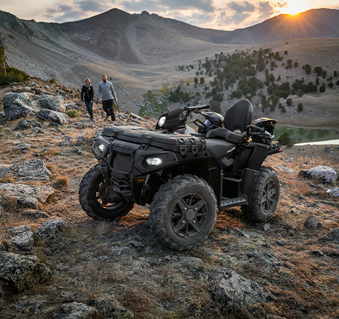 2 people walking toward their 2027 Polaris Sportsman Touring 850 Premium 2-up ATV with 6 gallons of integrated storage.