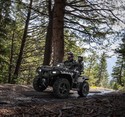 2 riders on a 2027 Polaris Sportsman Touring XP 1000 Trail 2-up ATV cruising through the forest.