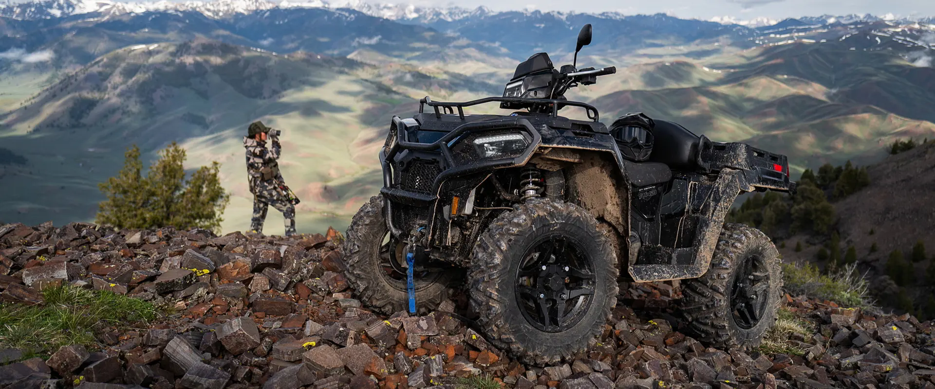A hunter looking over a ridge near their 2027 Polaris Sportsman X2 600 2-up ATV.