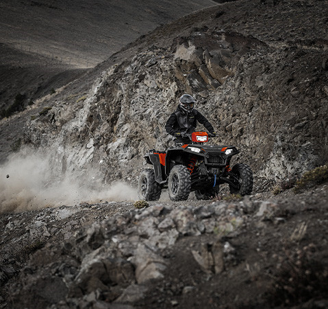 A rider on a 2027 Polaris Sportsman XP 1000 S ATV with headlights illuminated.