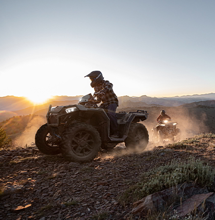 2 riders cruising at dusk with their 2027 Polaris Sportsman XP 1000 ATVs with illuminated headlights.