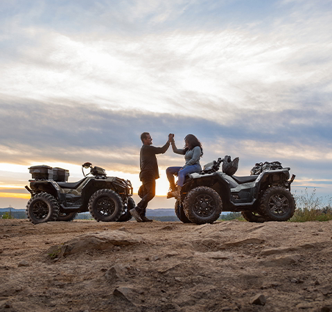 2 people clasping hands after a ride on their 2027 Polaris Sportsman XP 1000 ATVs.