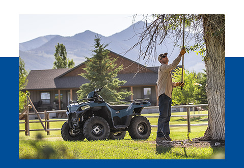 A man cutting the brances from a tree, his sportsman parked nearby