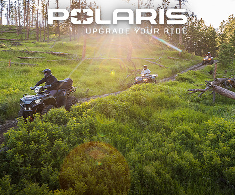 Polaris Sportsman ATVs riding across an open field