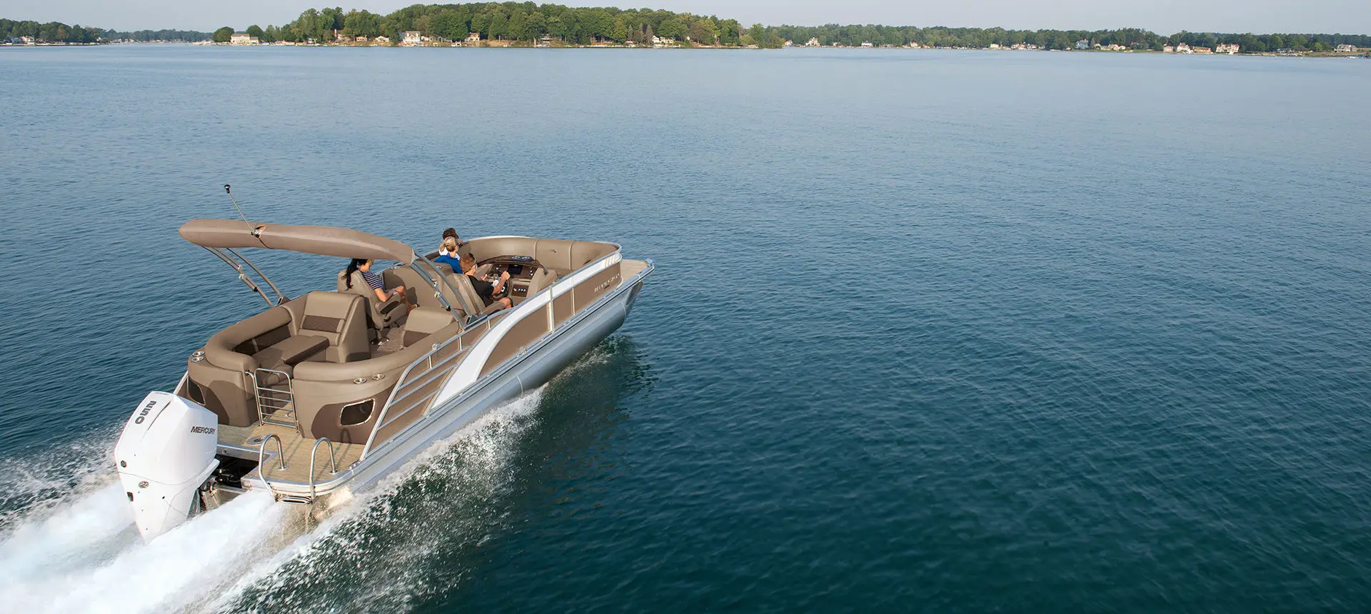 rear view of a bennington l bowrider pontoon boat cruising on a lake