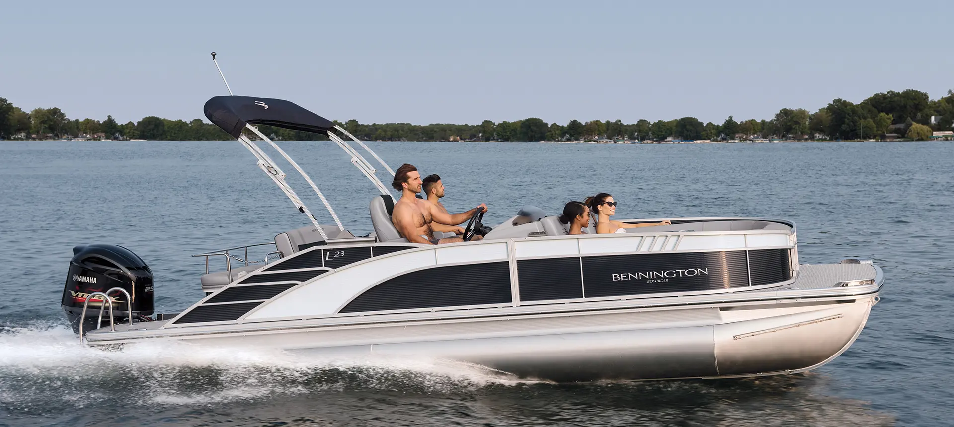 Side view of a bennington l bowrider pontoon boat cruising on a lake