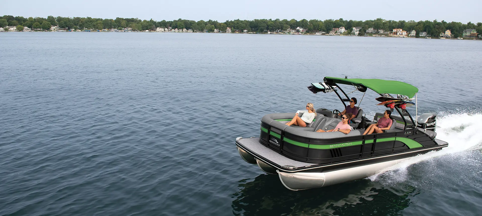 green and black bennington lx pontoon boat cruising on a lake