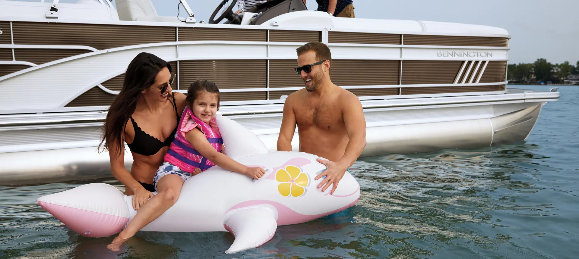 family playing in the water near their Bennington LX pontoon