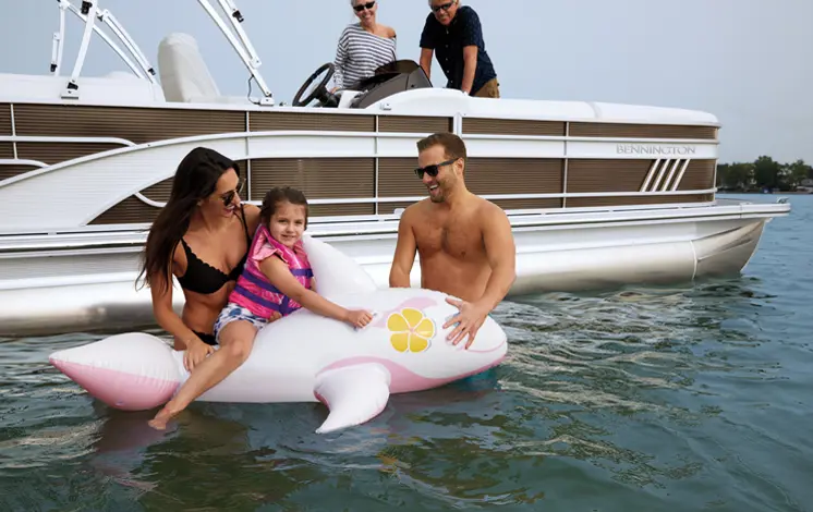 family playing in the water near their Bennington LX pontoon