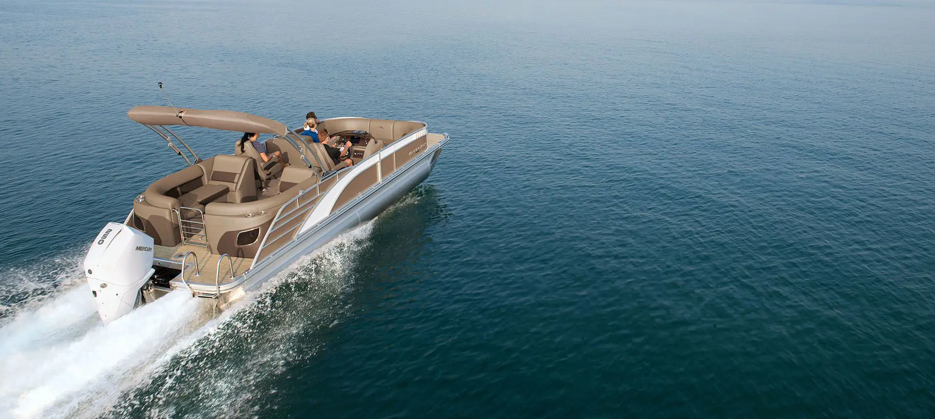 rear view of a bennington l bowrider pontoon boat cruising across a lake