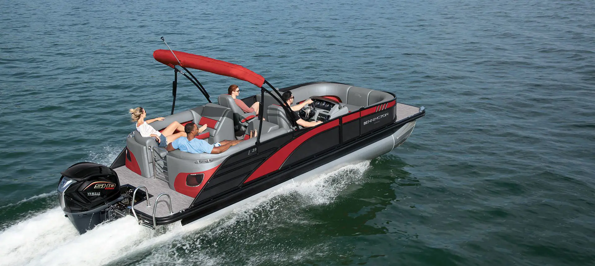 aerial/side profile view of a bennington l bowrider pontoon boat cruising on a lake