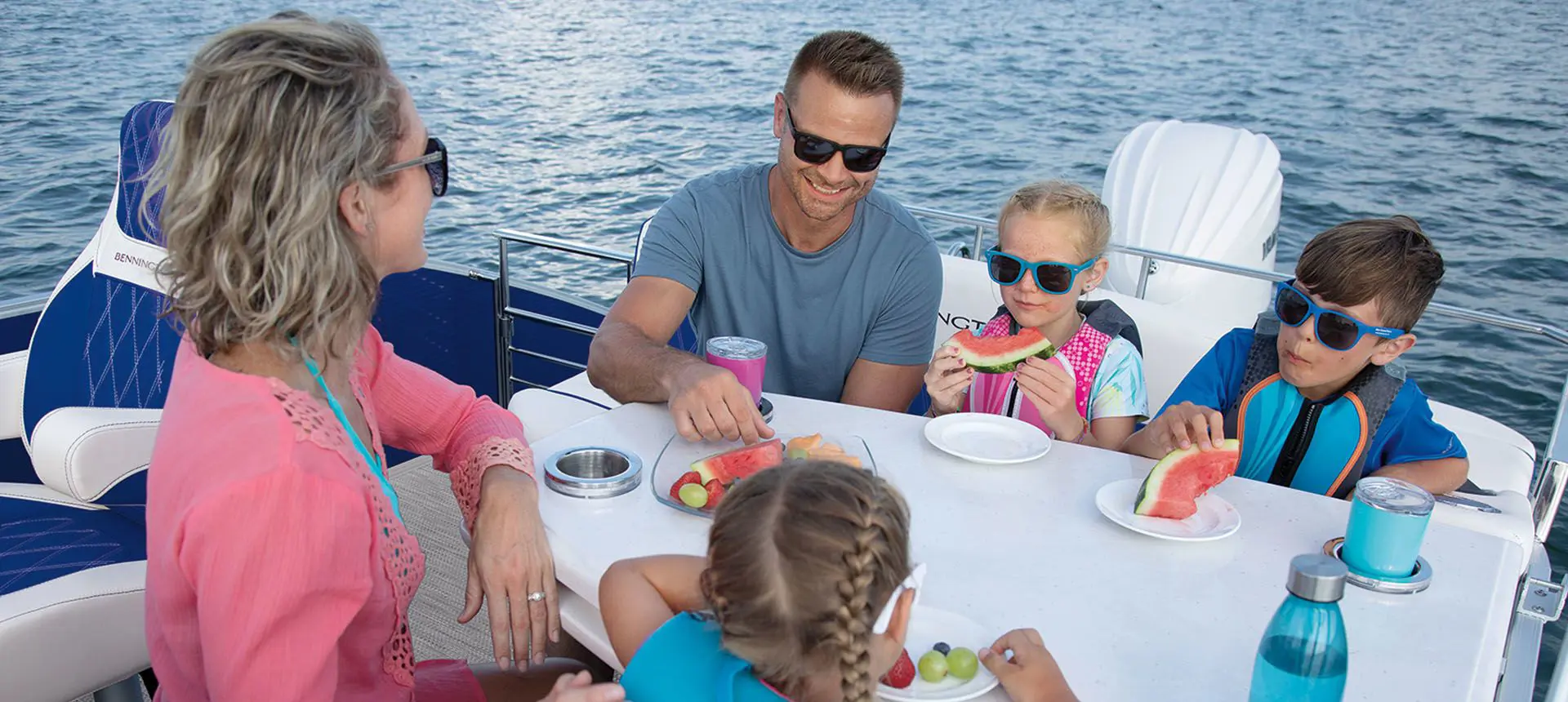 family sitting at the table on a bennington lx pontoon boat with entertainment floor plan