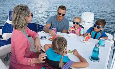family sitting at the table on a bennington lx pontoon boat with entertainment floor plan