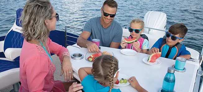family sitting at the table on a bennington lx pontoon boat with entertainment floor plan