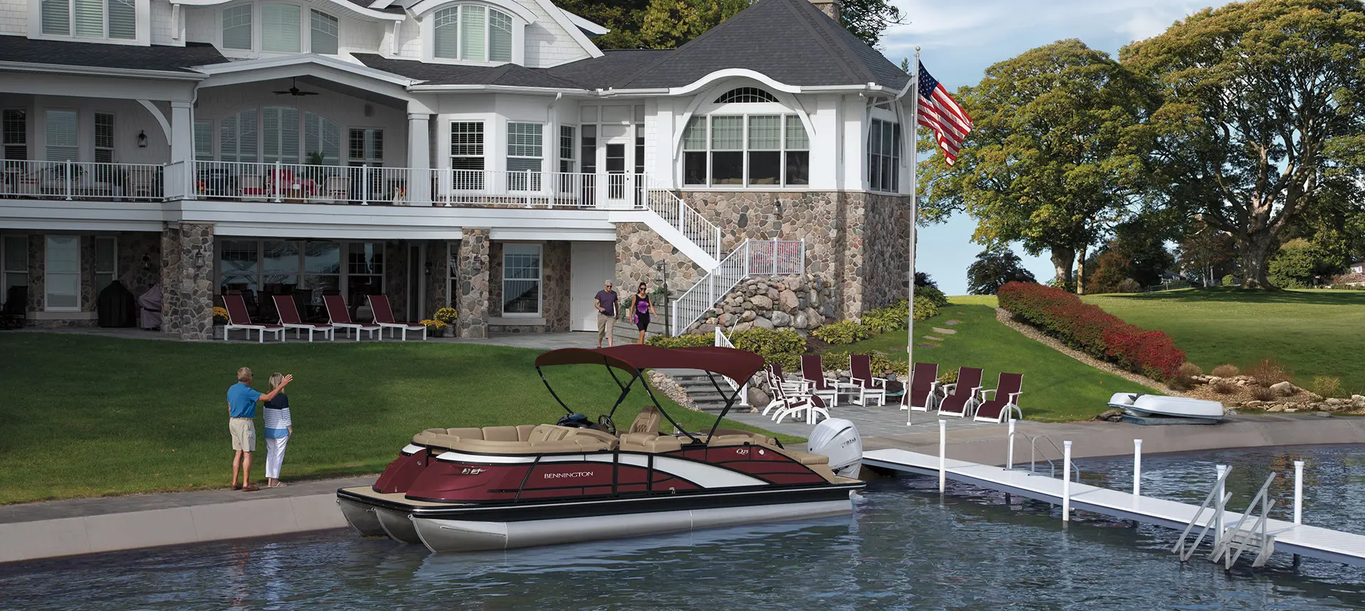 a couple waving near a docked bennington q pontoon boat