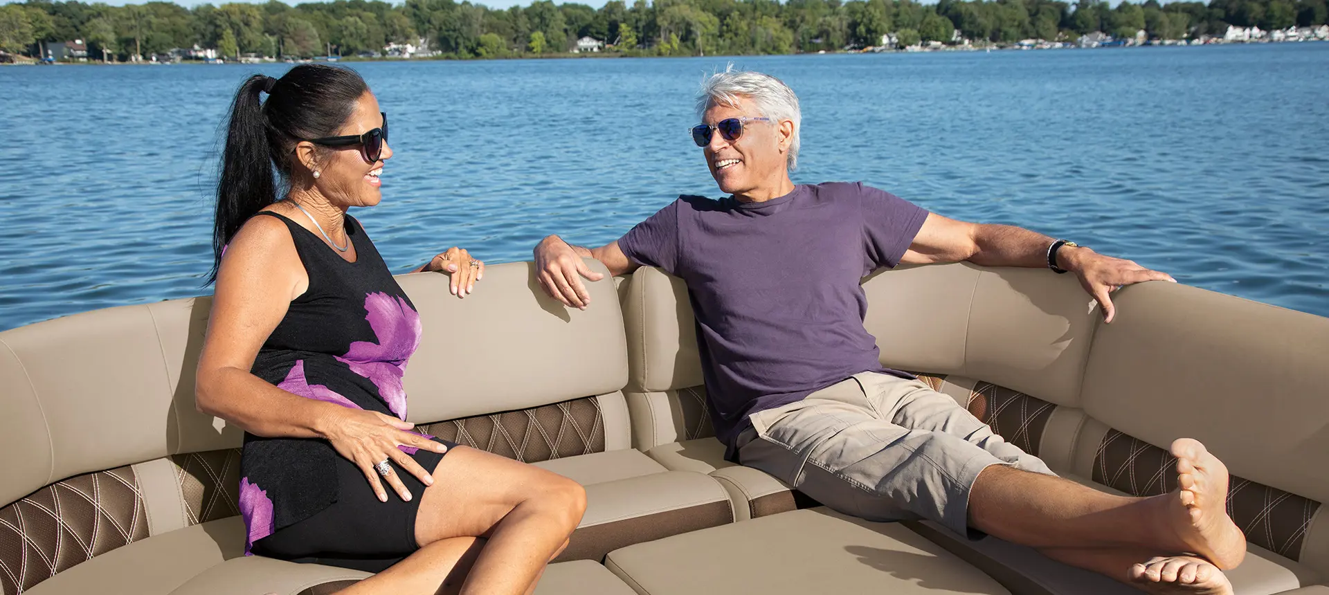 a couple smiling at each other and relaxing on the bow of a bennington q pontoon boat