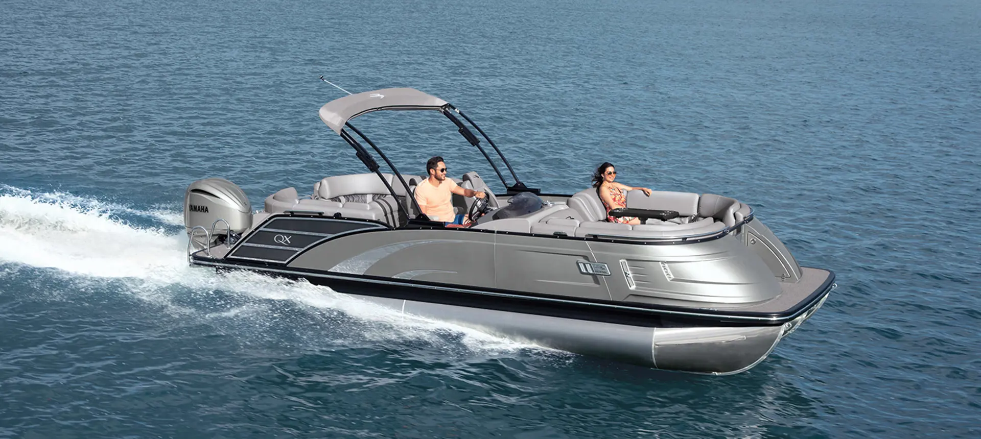 A happy couple enjoying a ride on a Bennington QX