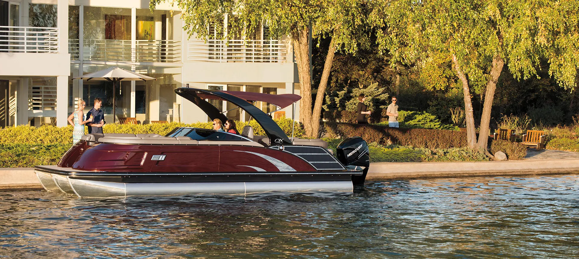 Bennington QX pontoon docked on a lake near a house