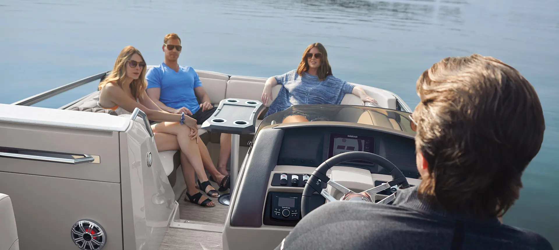 A man driving a Bennington R Bowrider Pontoon Boat while three friends relax on their seats