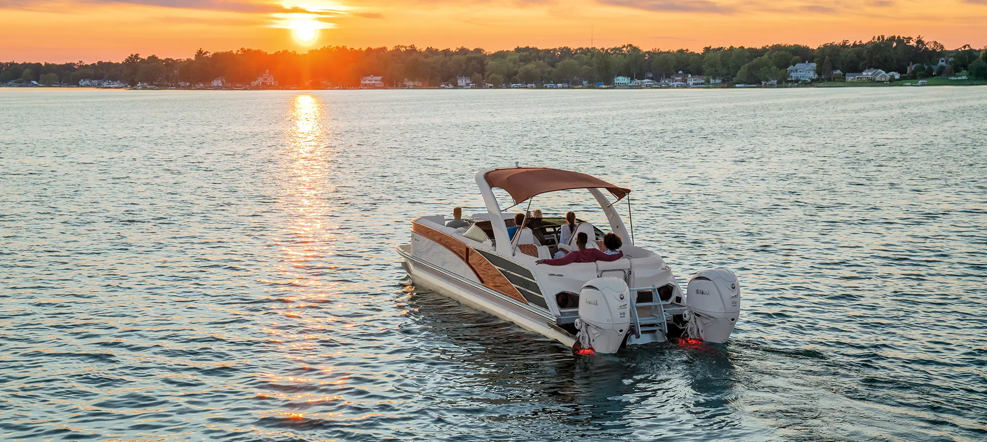 rear view of a bennington rx sport pontoon boat floating on a lake at sunset
