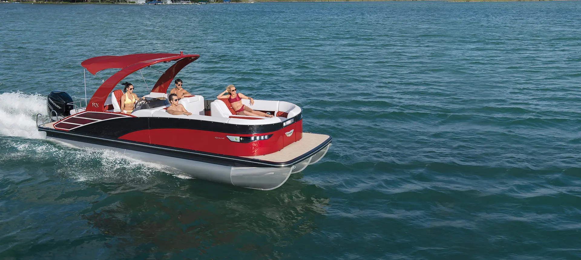 side view of a red bennington rx sport pontoon boat cruising on a lake