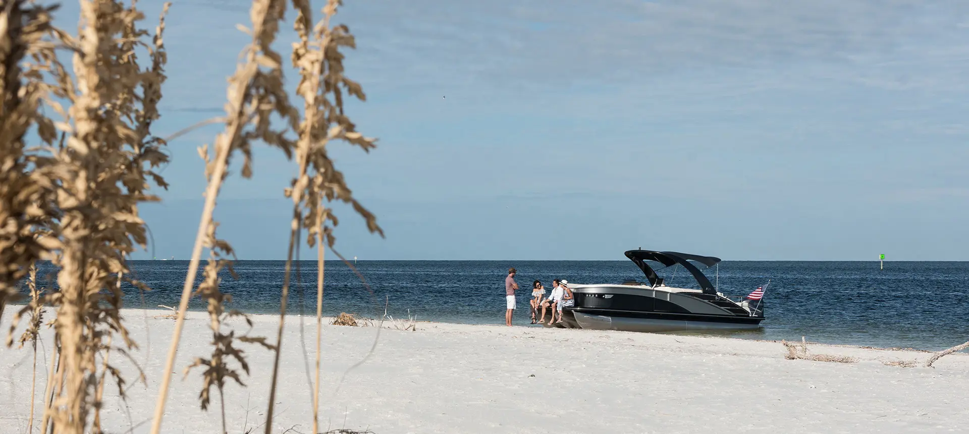 group of friends chilling on a Bennington RX Sport pontoon boat in the beach