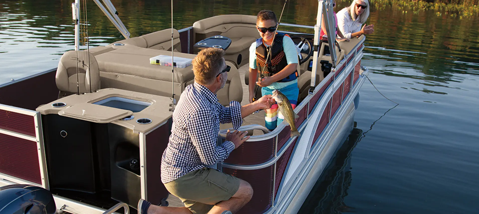 man catching a fish on the stern of a bennington s pontoon boat with fishing layout