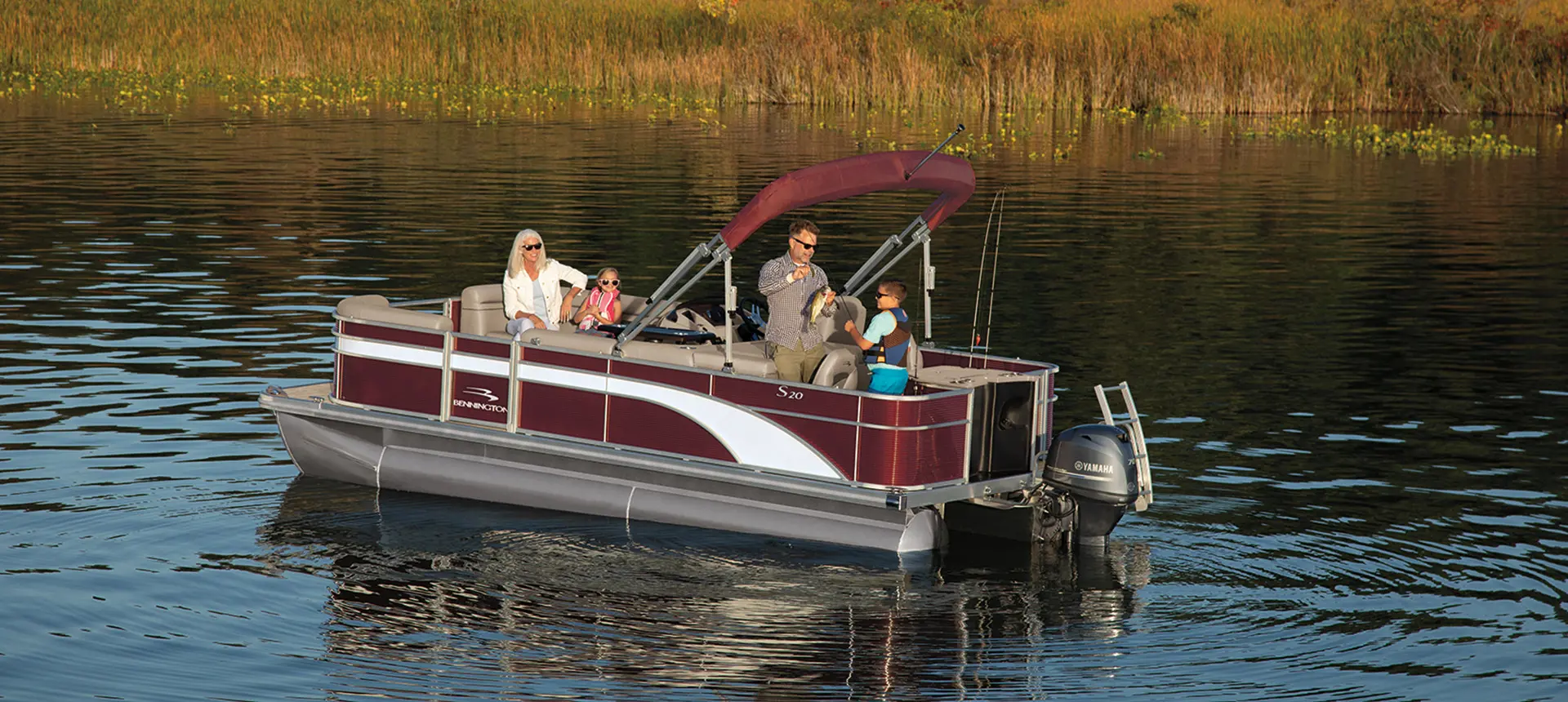 man showing a boy a fish on a bennington s pontoon boat