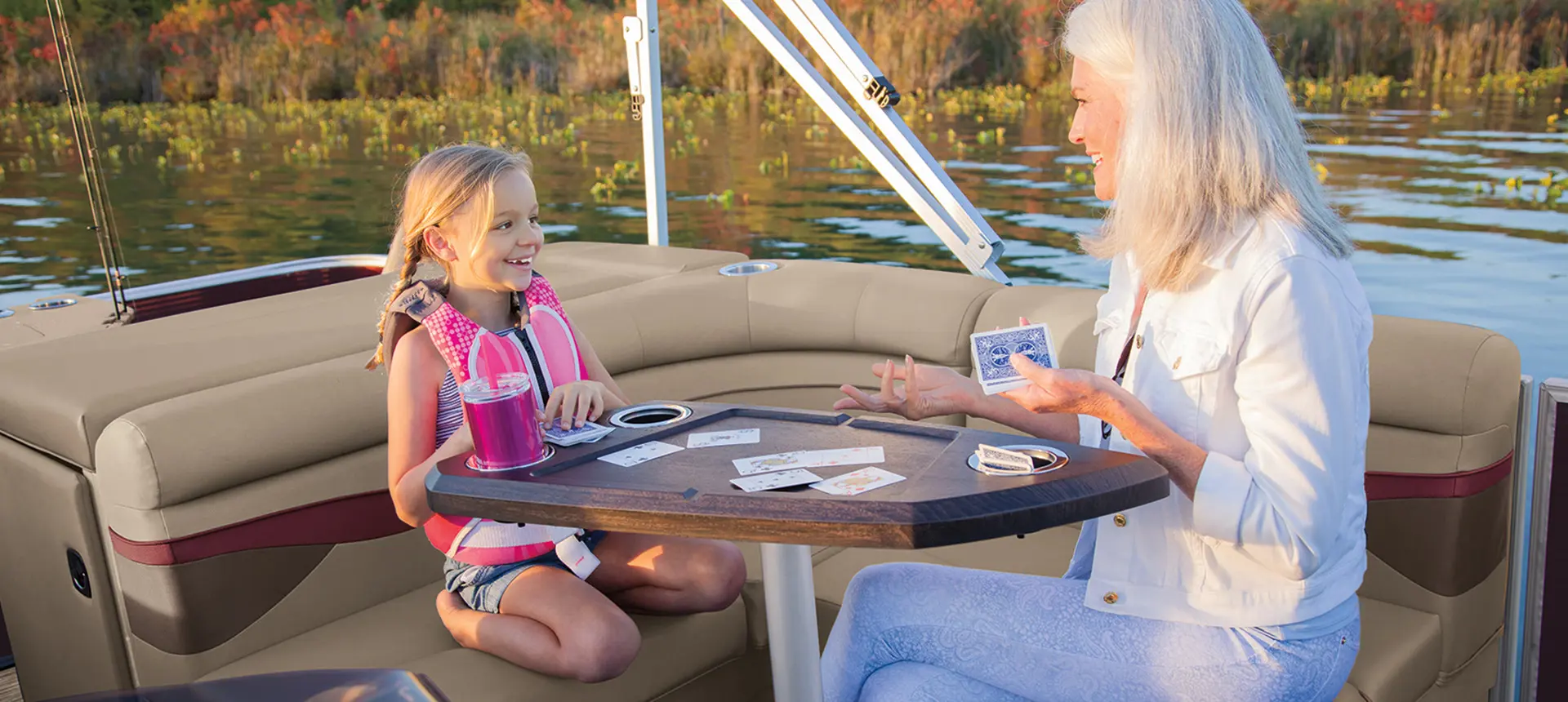 2 people playing cards on the table on a Bennington S pontoon boat with l-bench floor plan