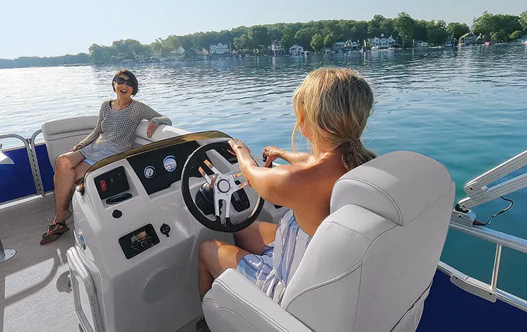 woman sitting at the helm of a Bennington SV pontoon boat and talking with another friend