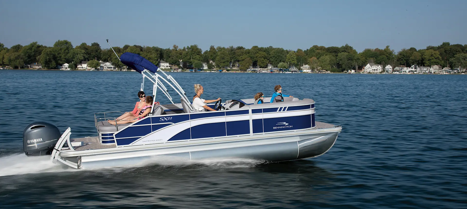 side view of a family cruising a lake on a bennington sx pontoon boat