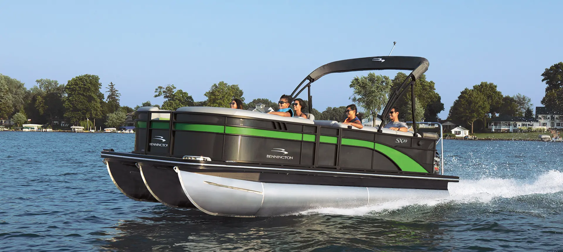 side view of a black and green bennington sx pontoon boat on a lake